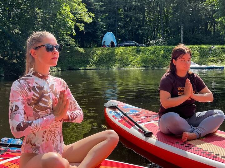 Практика на SUP-досках посреди воды у лесного берега